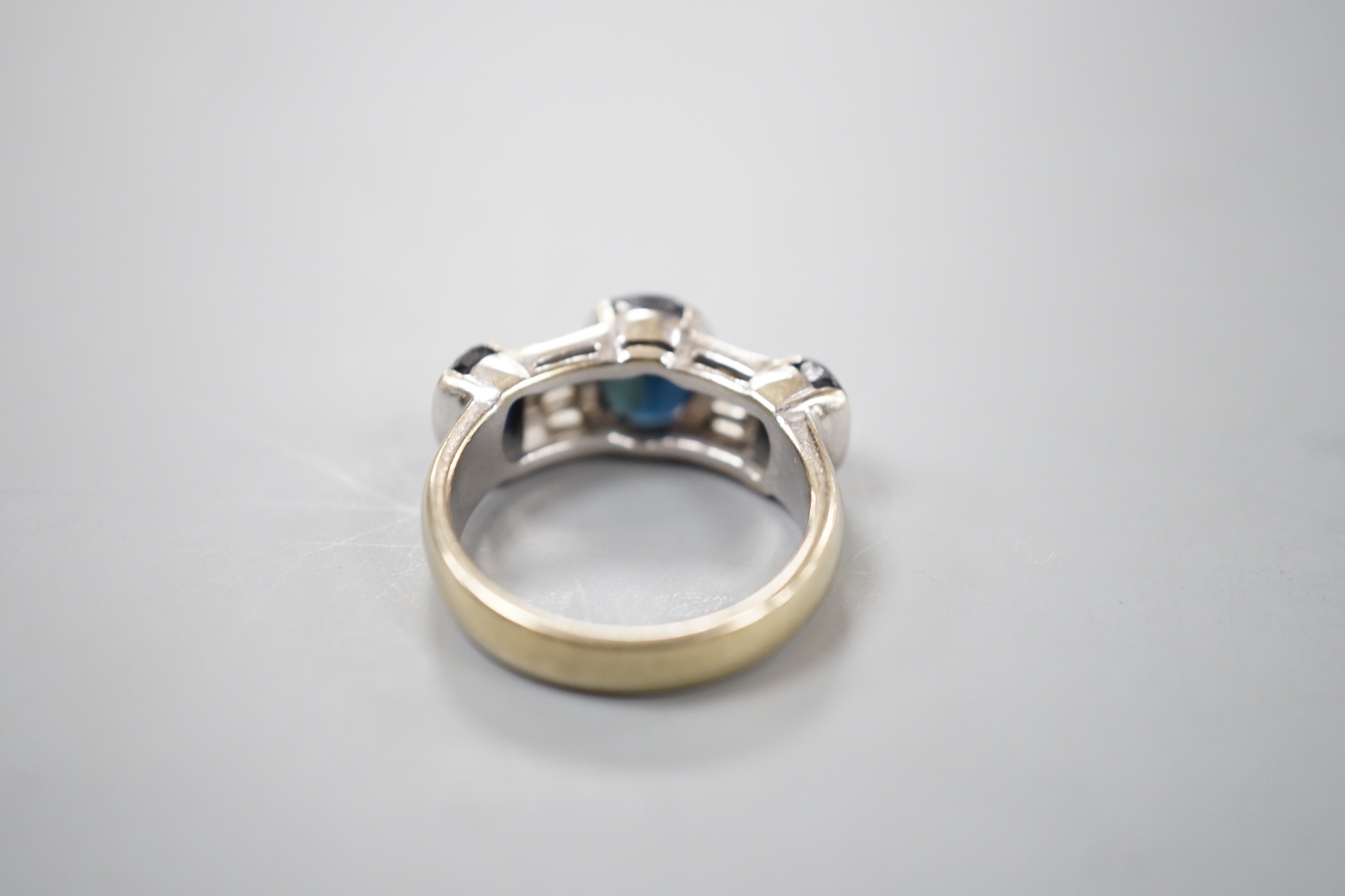 A yellow metal, three stone oval cut sapphire and eight stone trapeze cut diamond set half hoop dress ring, size Q, gross 9.2 grams.